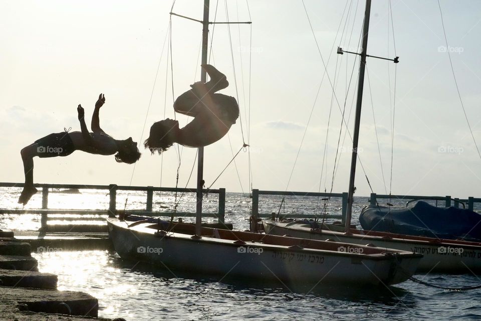 Father and son doing somersault together jump from the dock