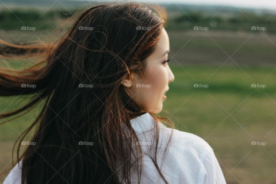 Close up portrait of beautiful carefree long hair girl in white clothes in nature field, view from back. Sensitivity to nature concept