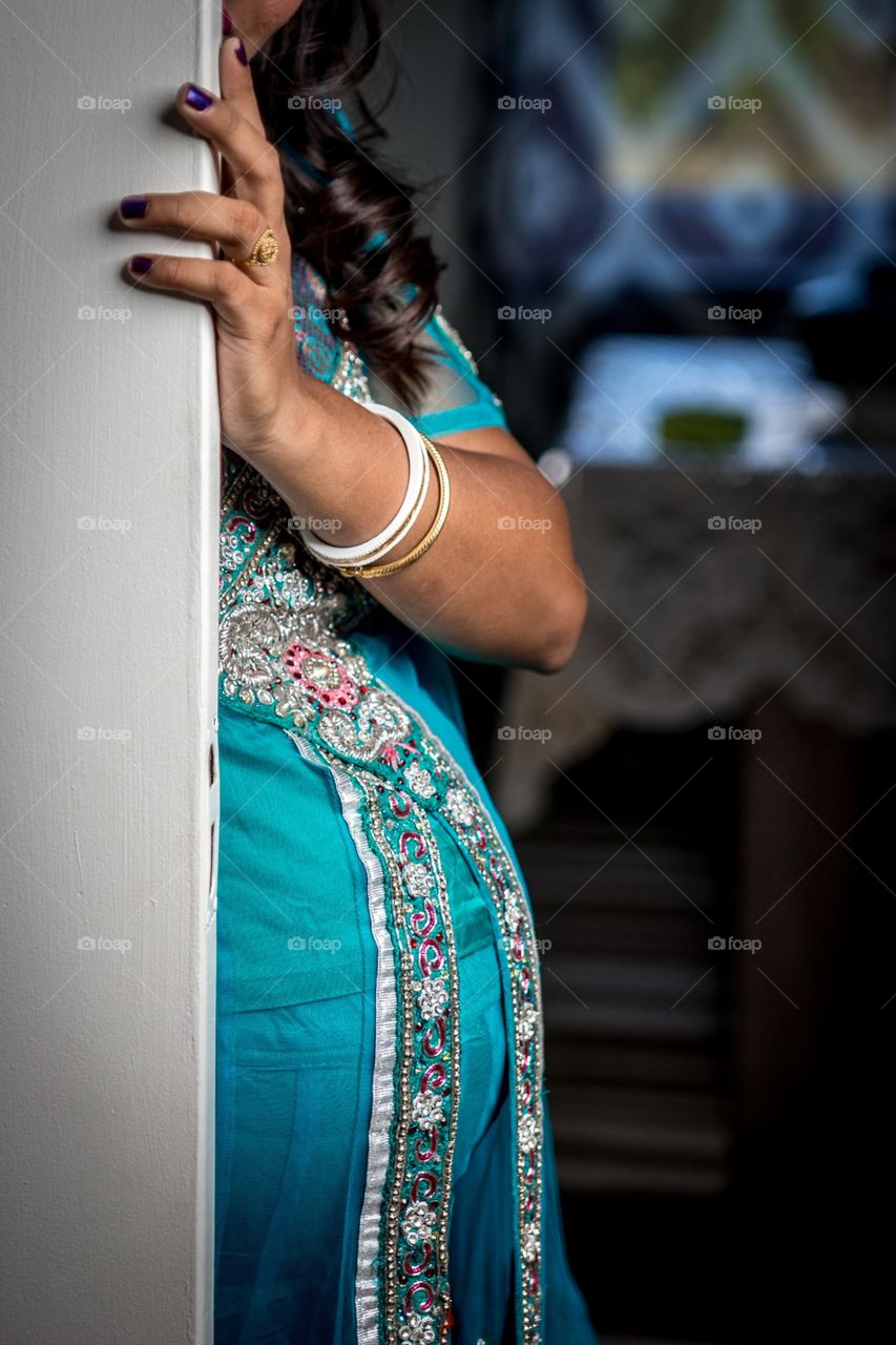 An Indian woman showing her belly behind a door, shy moments