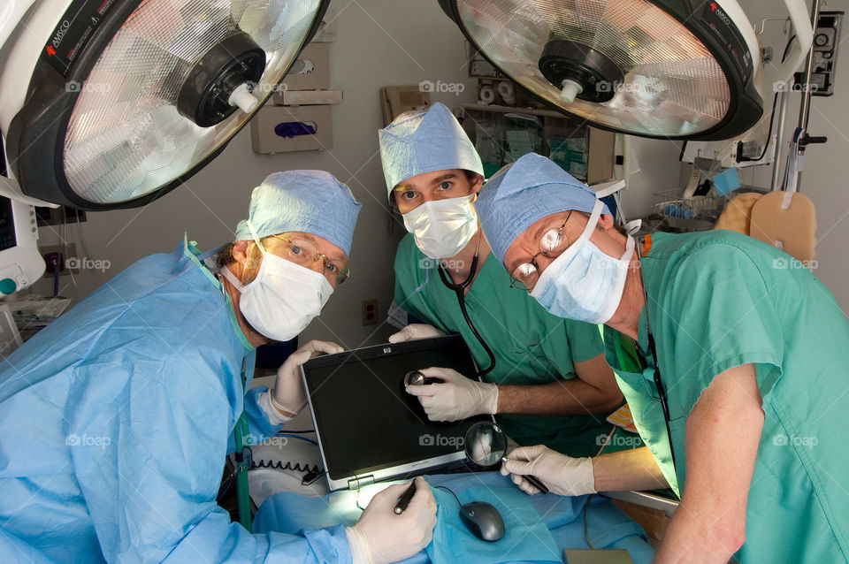 Three men operate on a computer in an emergency room hospital