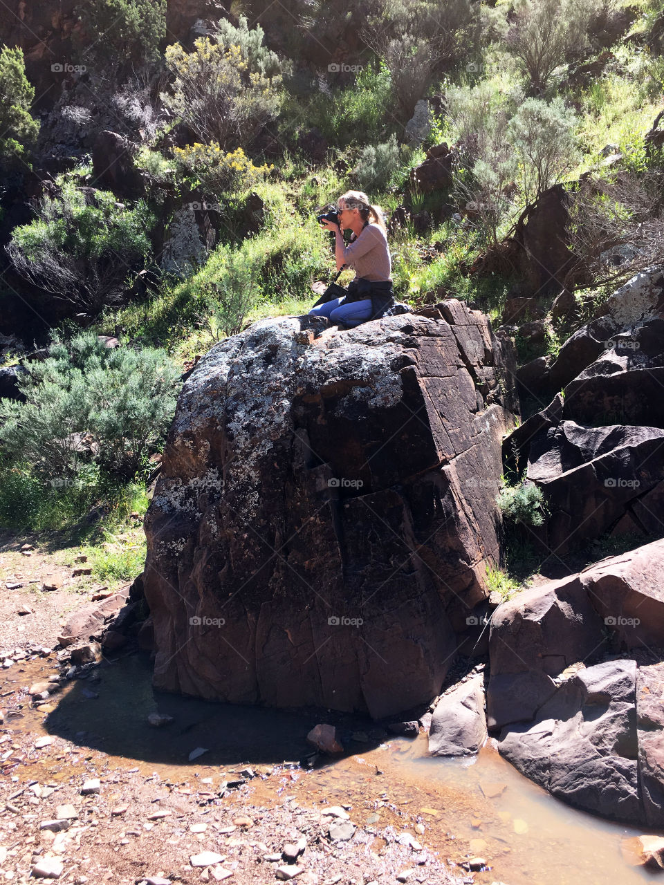 Woman sitting on rock photographing