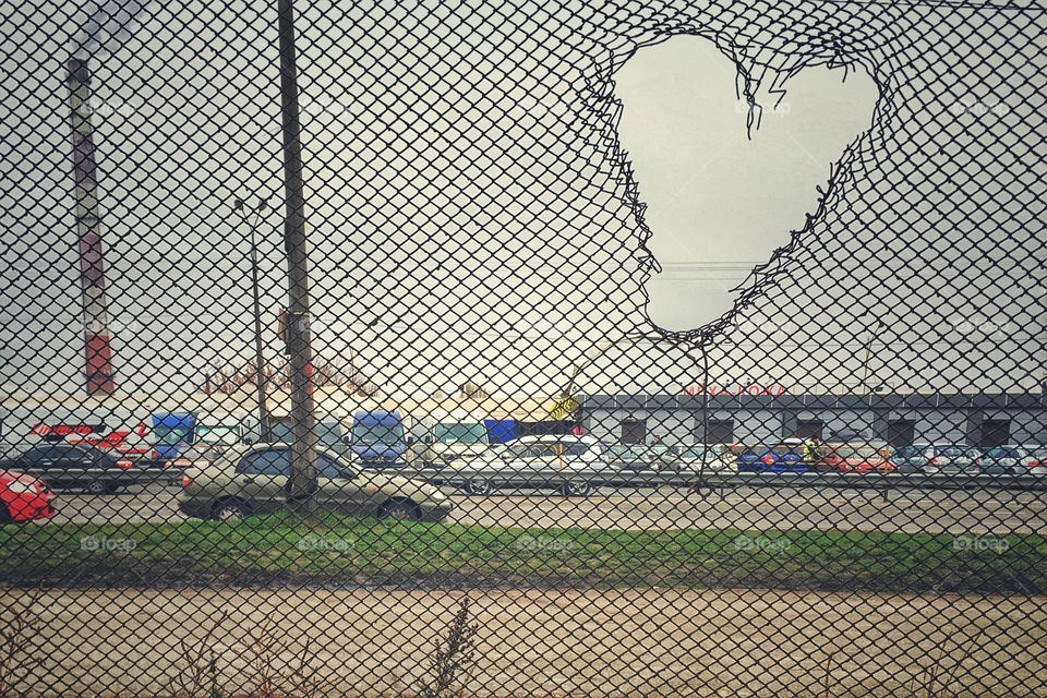 A hole in the form of a heart in a metal fence. 