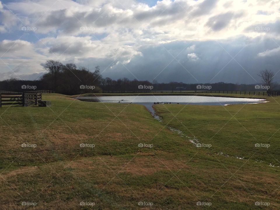 Pond at the end of the road with cool sky clouds and horizon 