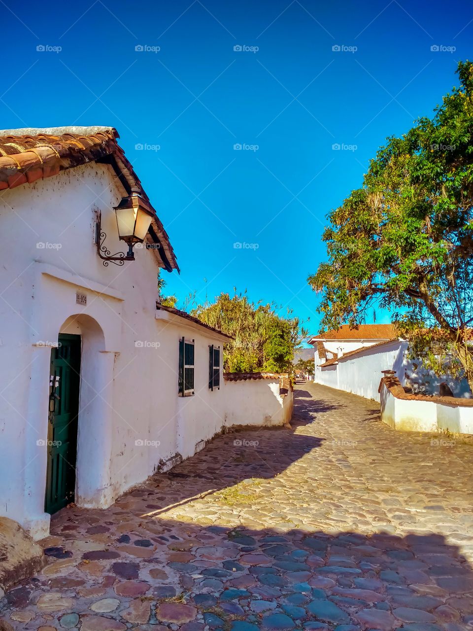 Calle empedrada de Villa de Leyva, Boyacá, Colombia en una mañana soleada y de cielo azul. Arquitectura colonial. Cobbled street in Villa de Leyva, Boyacá, Colombia on a sunny morning with blue sky. Colonial architecture. Beautiful travel destination