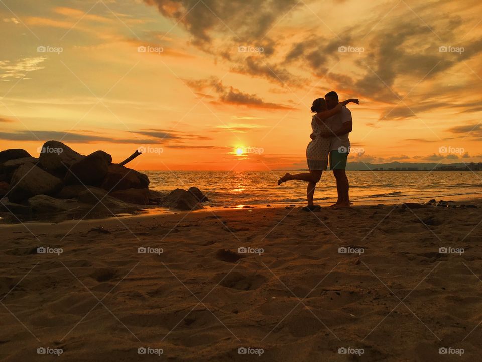 Silhouette of couple kissing on beach at sunset