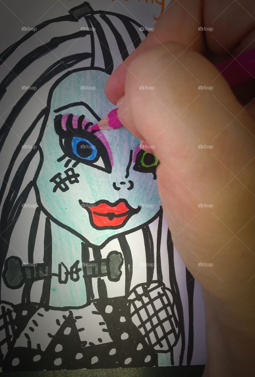 A hand shading in color on a drawing of Frankie Stein off of Monster High. 