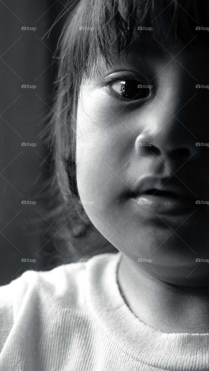 Black and white portrait of a little Asian girl with a flat expression.