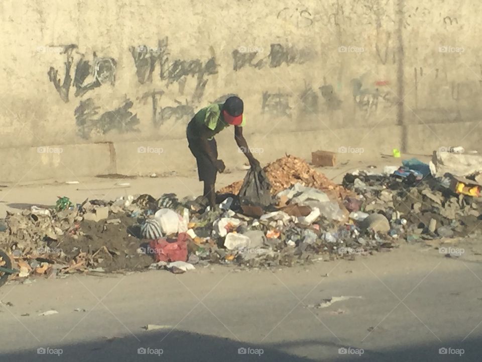 Haitian man digging through trash in Port-au-Prince
