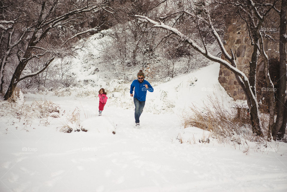 Man and girl running on snowy landscape