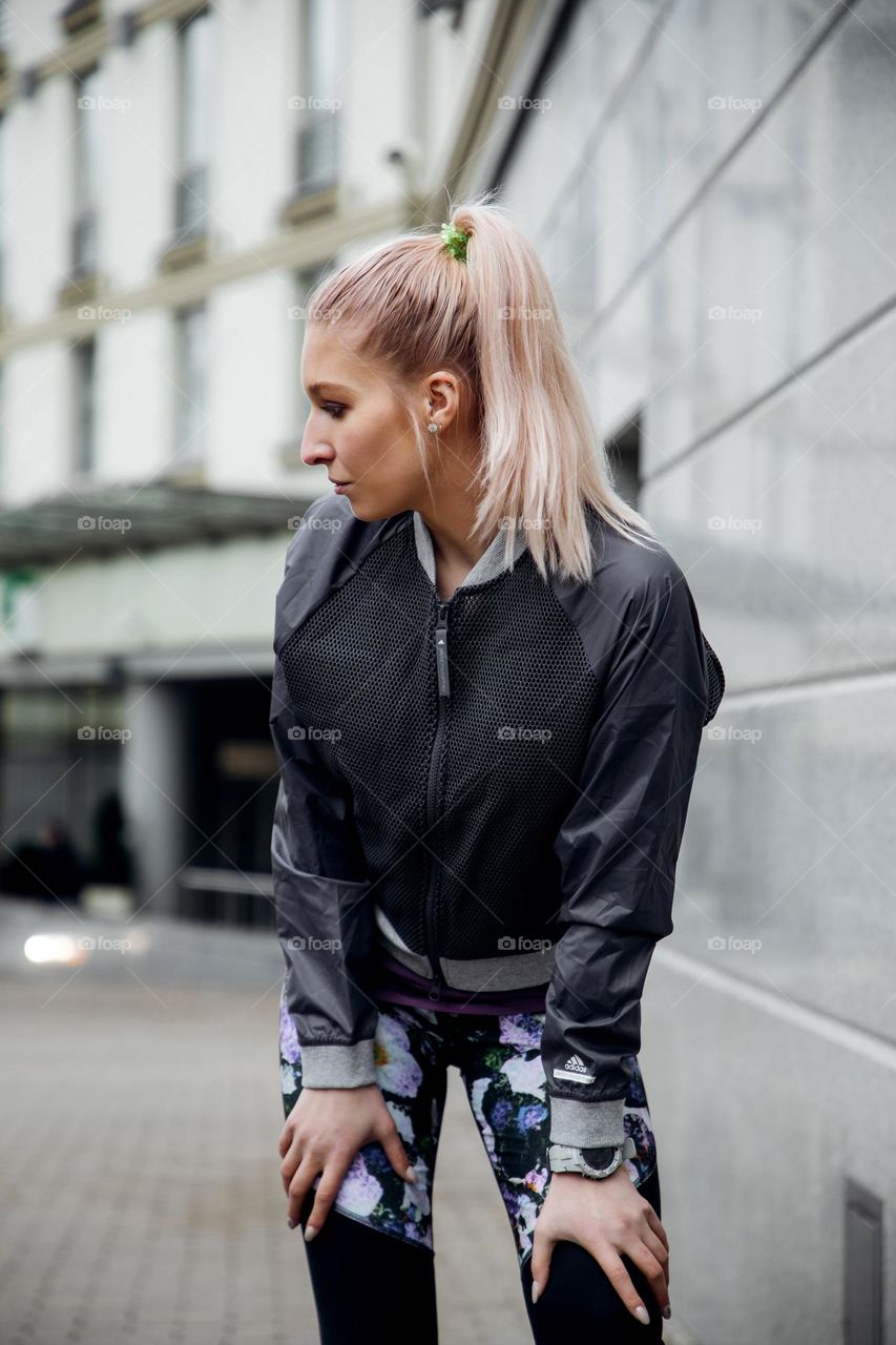 Blonde sports girl with ponytail training outside on the street