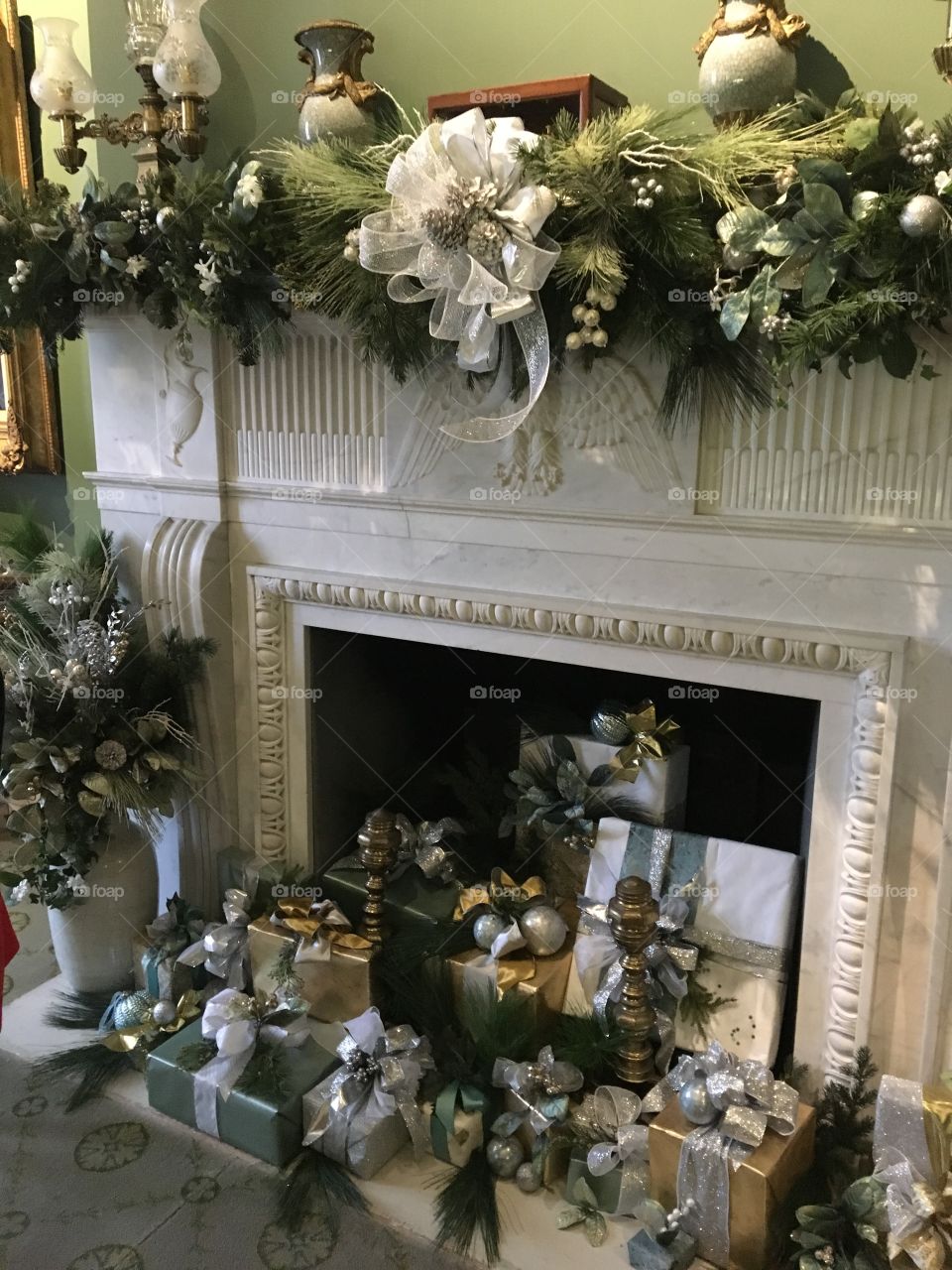 A lavishly decorated fireplace that is ready for Christmas. Freshly wrapped gifts sit in wait