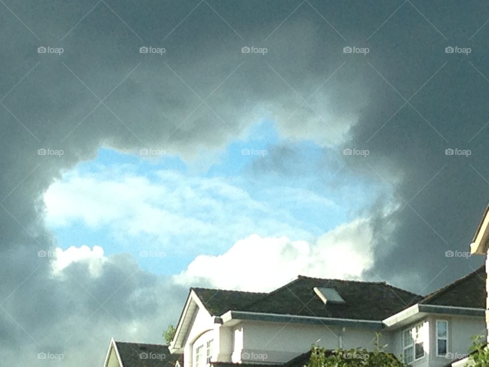 Blue sky portal. A blue sky portal through dark clouds over luxury homes on mountain, metaphor perhaps for real estate or mortgage rates