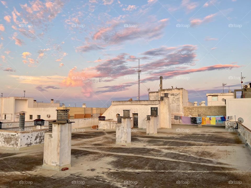 Sunset sky view from rooftop perspective with chimneys and laundry to dry 