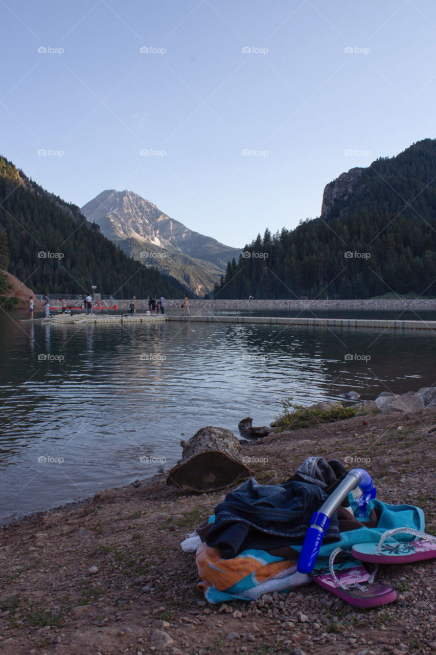 A pile of clothes left on the shore while enjoying a leisurely swim in the clear waters of a mountain reservoir. 