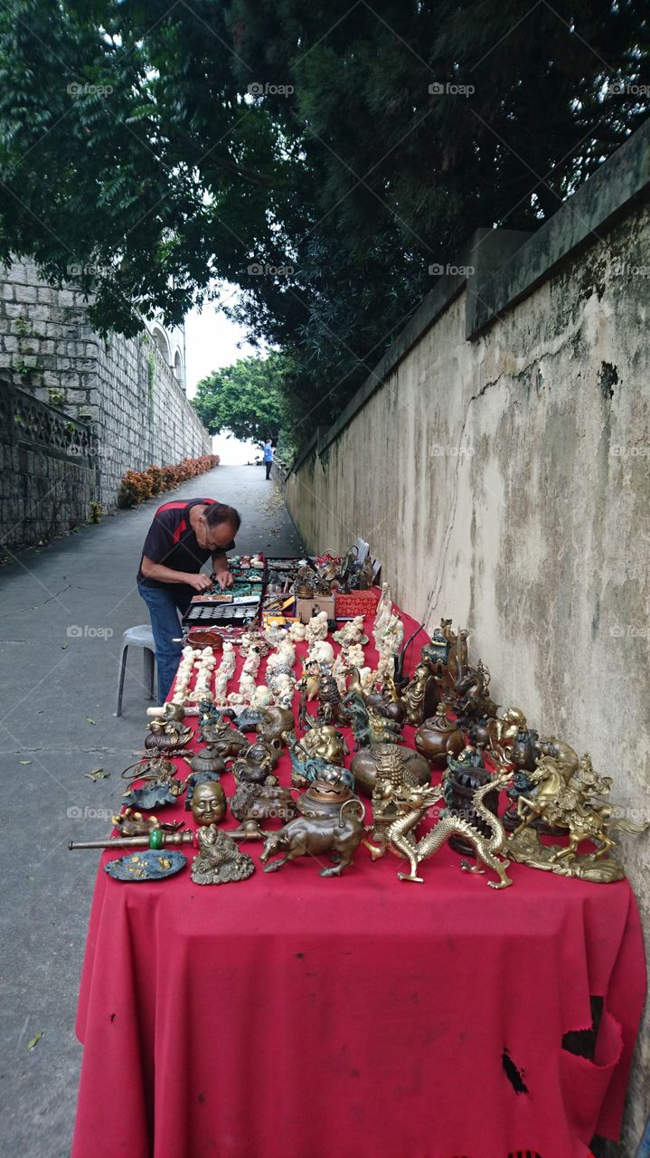 an old man selling the antique statue near  the Chapel of Lady of Penha,