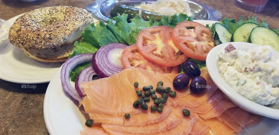 Extremely satisfying lox and everything bagel platter, with lox, red onions, tomatoes, lettuce, capers, olives, pickles, sauerkraut, potato salad