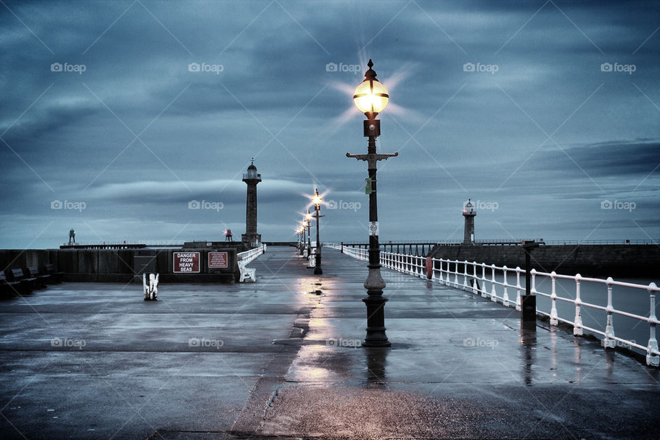 Lights dance on the cold wet pier.