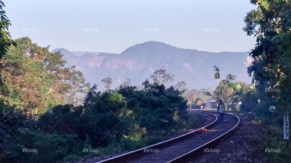 A beautiful scenery of  a railtrack and a mountain range of  Himalayan  foothills