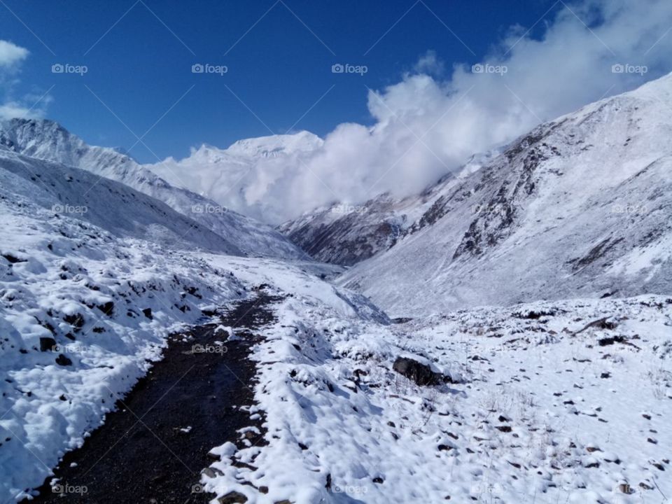 a big mountains covered with snow is very beautiful place to visit or to travel or for the tracking as well as the clouds are talking with the mountains as we can see in the photo.