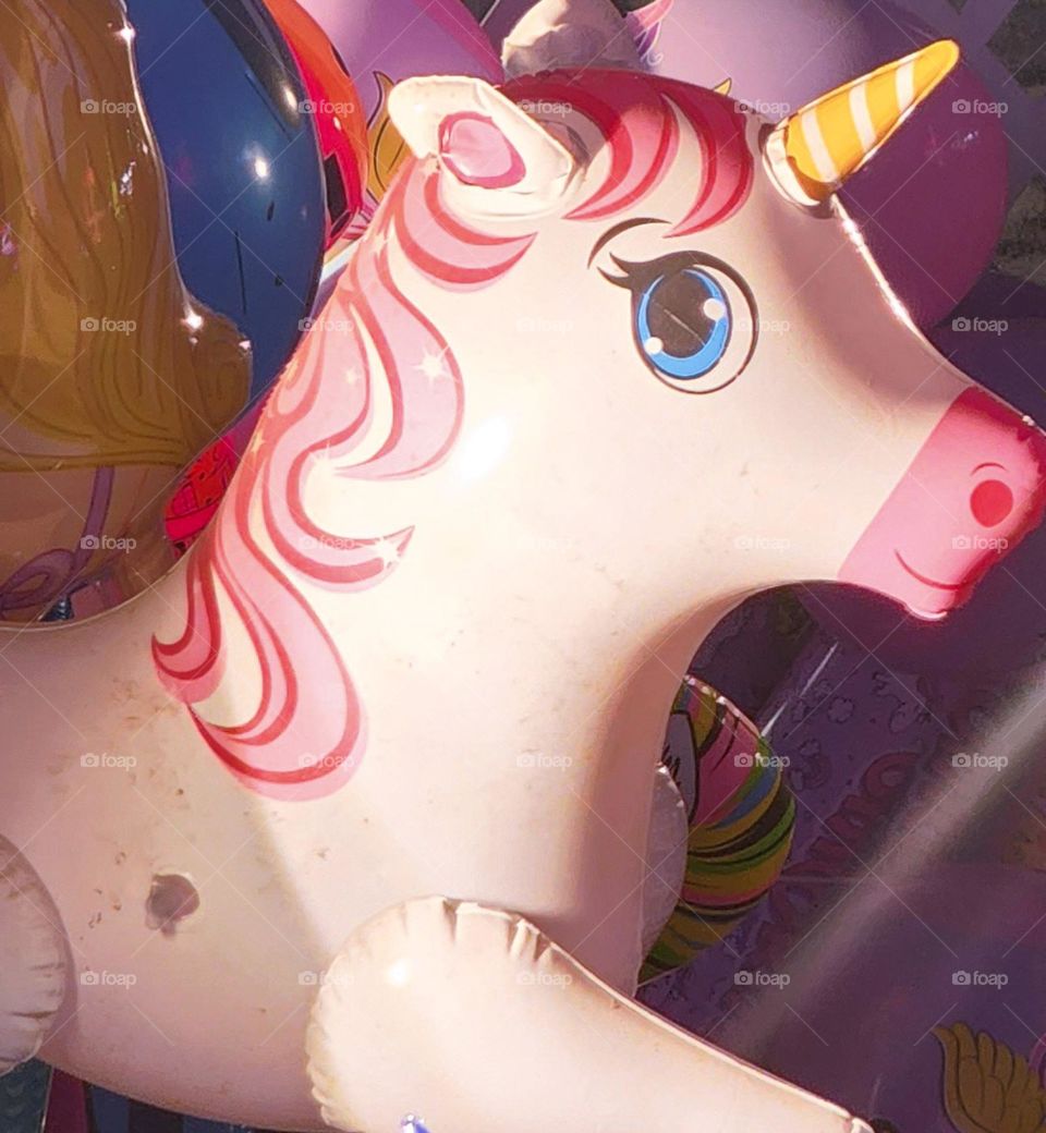 smiling blue eyed inflatable unicorn toy with pink barbie style hair at an Oregon fair