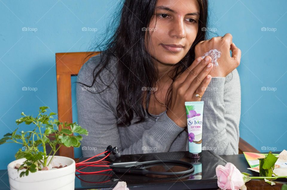 Woman after working for long, applying ST Ives hand cream at her work place.