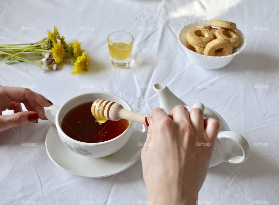 A woman adding honey in tea