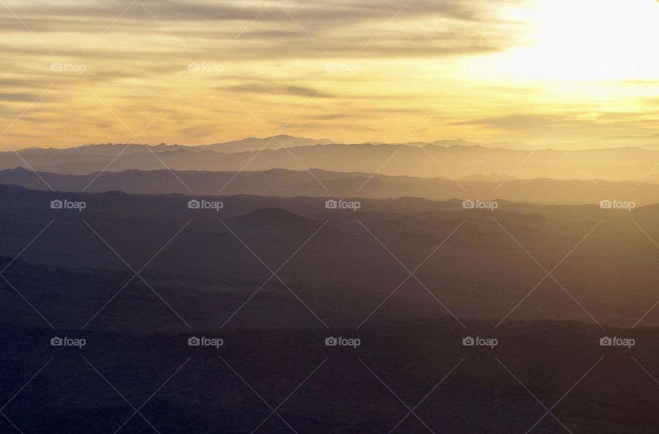 Yellow ombré sunset lighting clouds and mountains