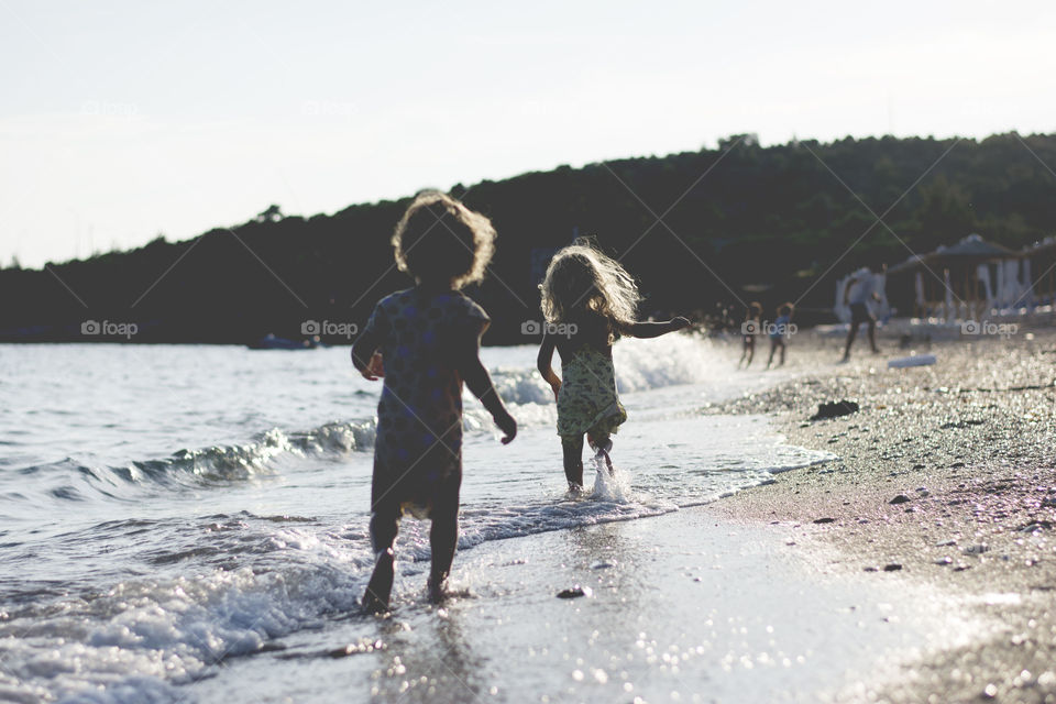 two kids running through water. two little kids  running at the beach through shallow water