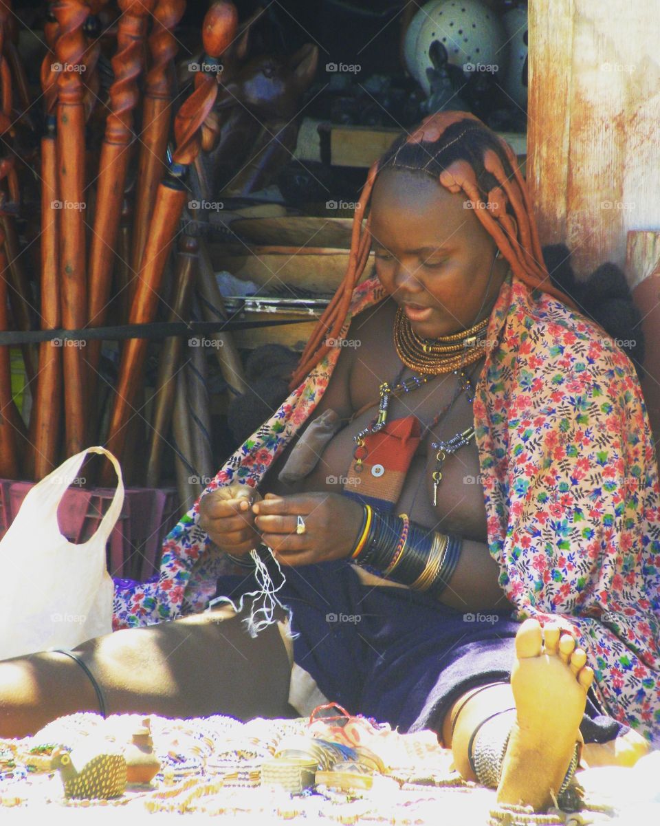 Poor African woman making jewelry