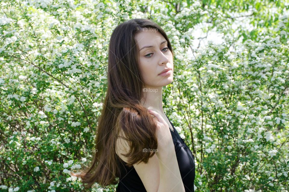 Beautiful Young Girl on Background of Flowers