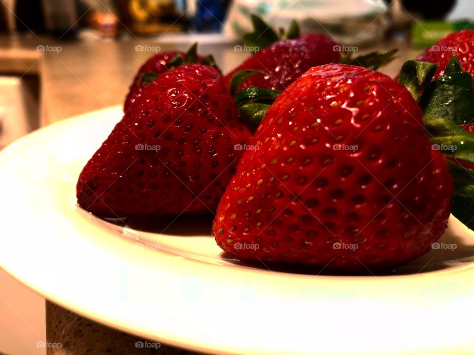 Red, plunk strawberries waiting to be diced, added to cream, and served with a moist chunk of shortcake 