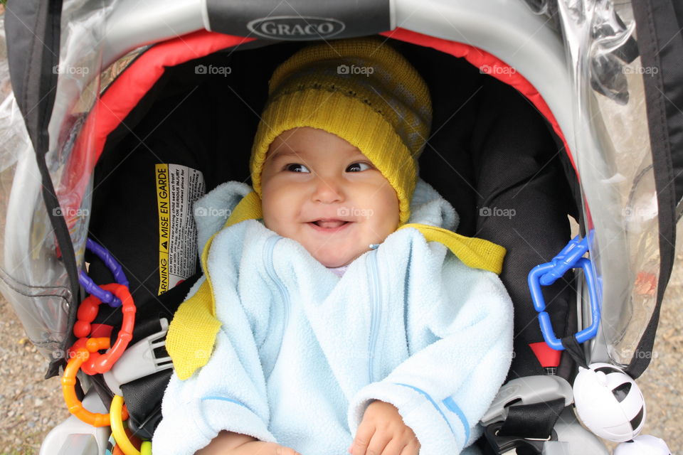 Front view of a happy baby girl sitting in a stroller