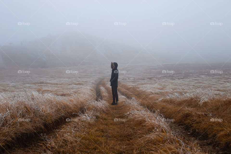 Man standing on field during foggy weather.