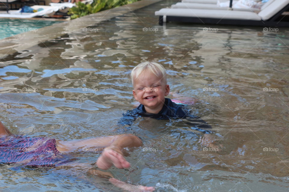 Funny little boy having fun on a pool 