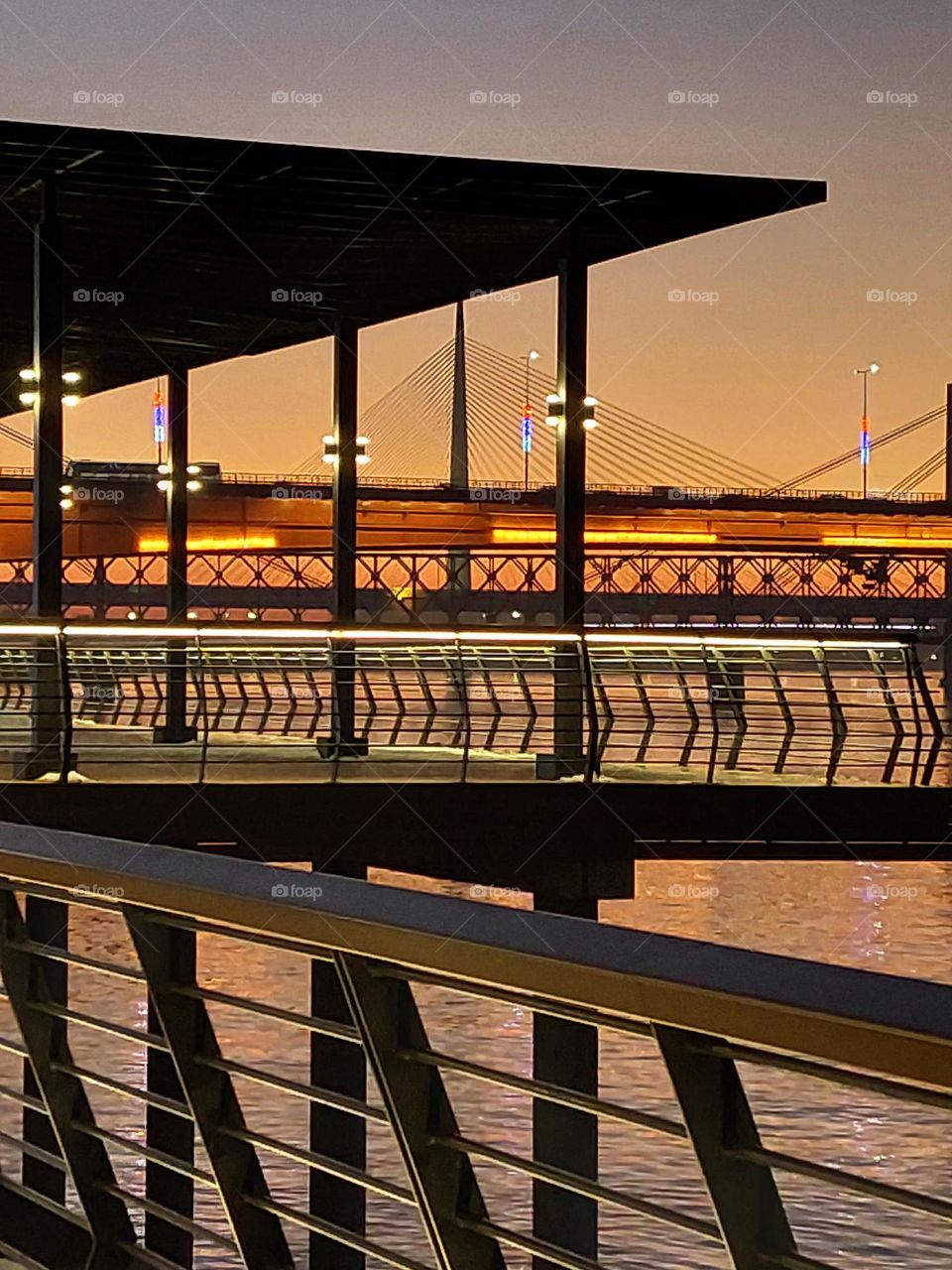 Cityscape in the evening.  View of the bridge and river through the fence.  Dominance geometric shapes: triangle and rectangle