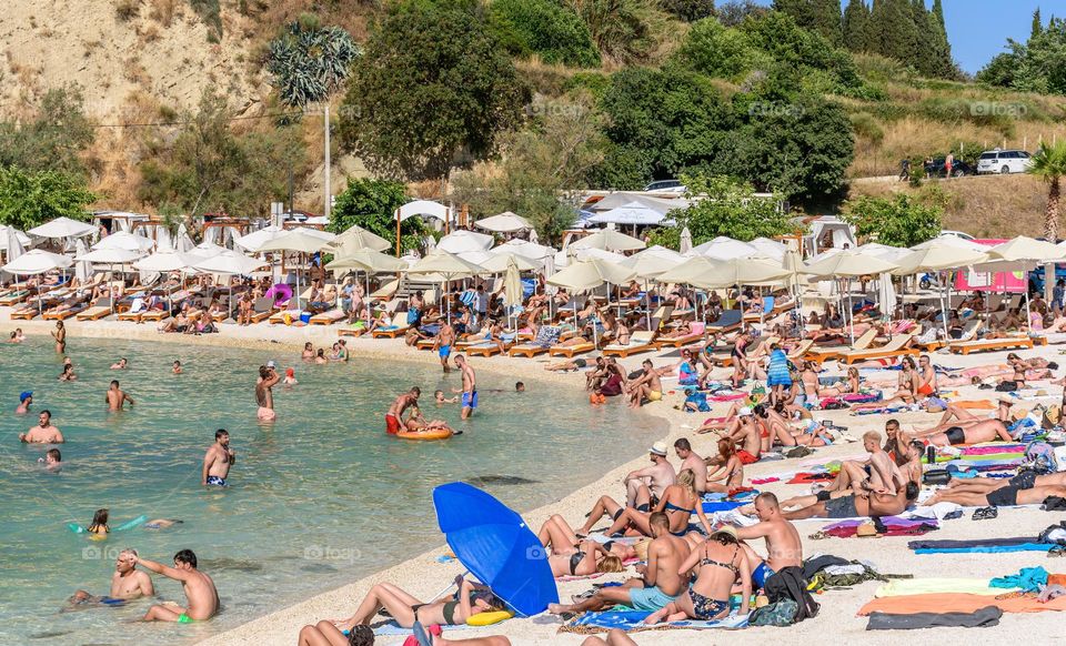 Crowds of people sunbathing on beach near Split in Croatia