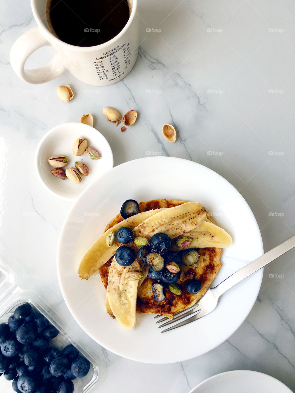 Healthy breakfast with fresh blueberries and banana french toast sprinkled with pistachios on a marble background 