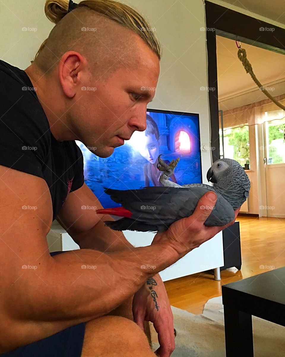 A man holding gray parrot sitting at home