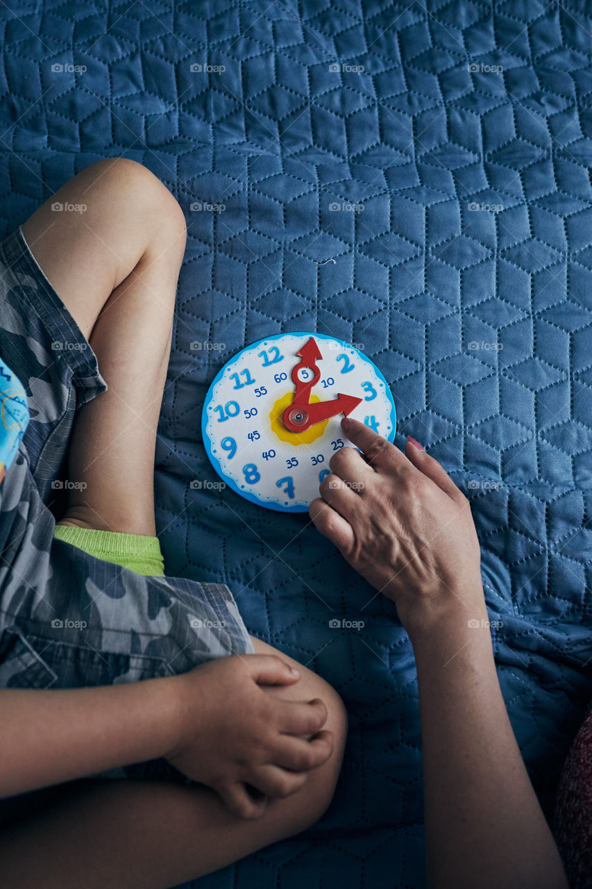 Kids learning how to tell time from clock and set the hands in the correct position. Teaching preschoolers tell time. Candid people, real moments, authentic situations