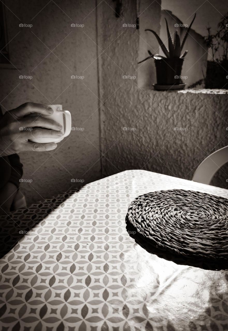 hand holding a cup, a table, a flowerpot