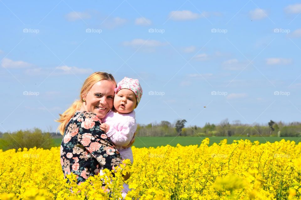 Woman holding her baby in a blooming flower meadow 