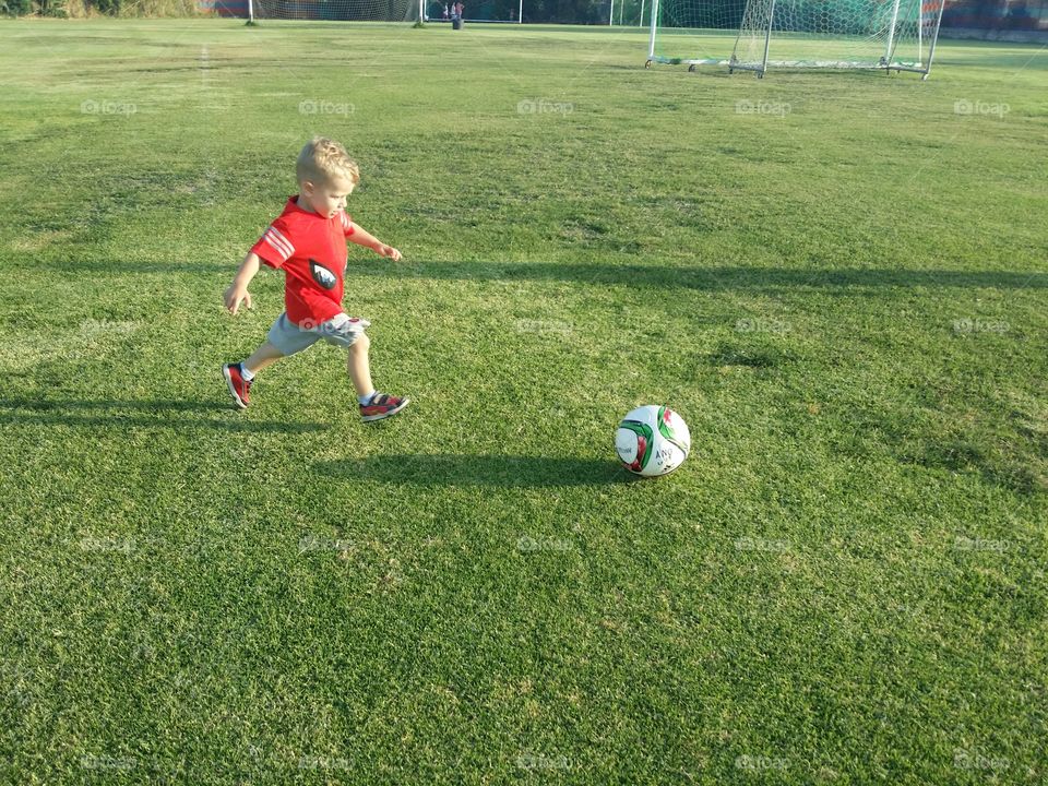 Boy playing football on grassy field
