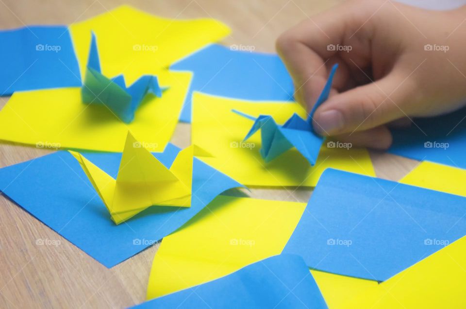 child folds paper cranes