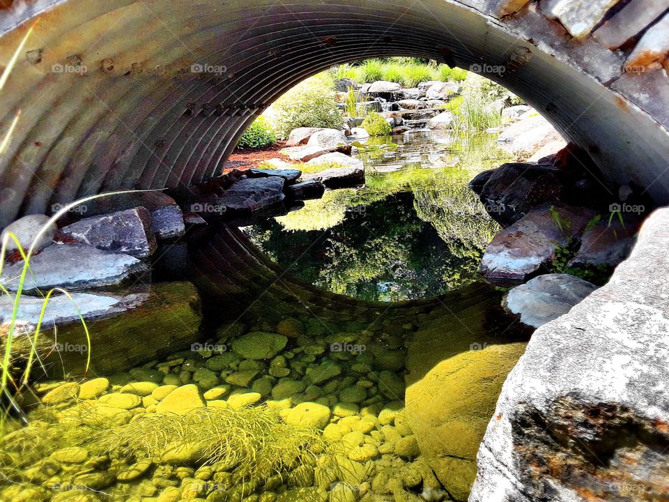 Small bridge over stream with small waterfall in the background