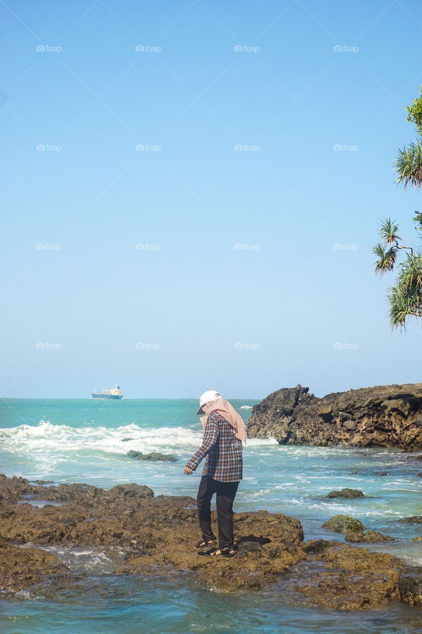 A girl is standing in the coral with a sea view on the background