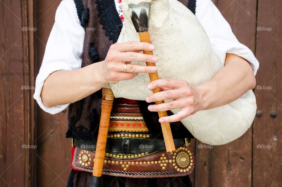 Young man dressed in Bulgarian traditional clothing (nosiya) playing bagpipes