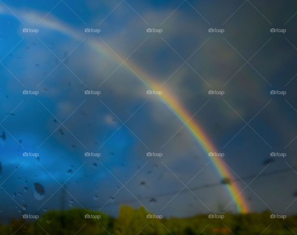 A blurry rainbow seen through wet glass
