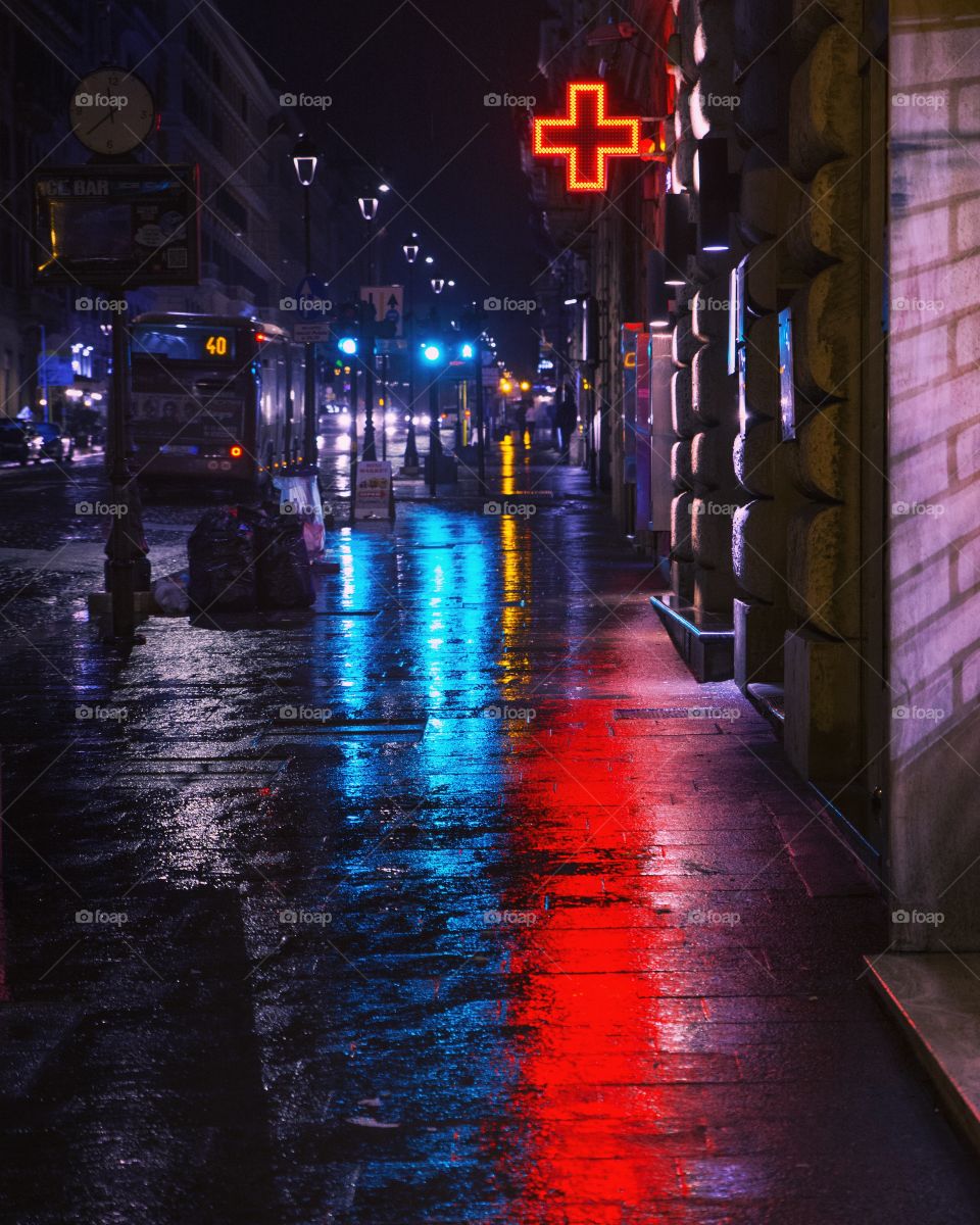 Neon lights in the rain on a Roman street at night