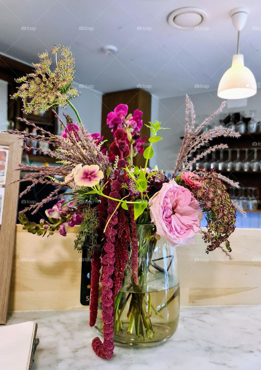 Close up of the beautiful bouquet with purple burgundy amaranthus and other species of flower and plants in glass jar with water as a vase