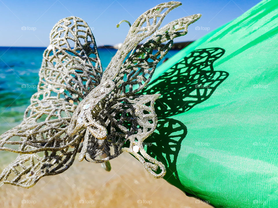 glittered DIY butterfly in front of sea